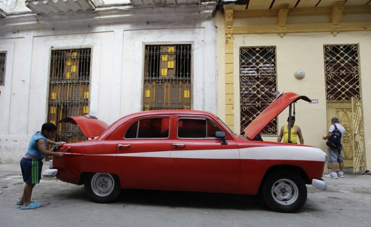 Image: A boy cleans his father's car on a street in Havana